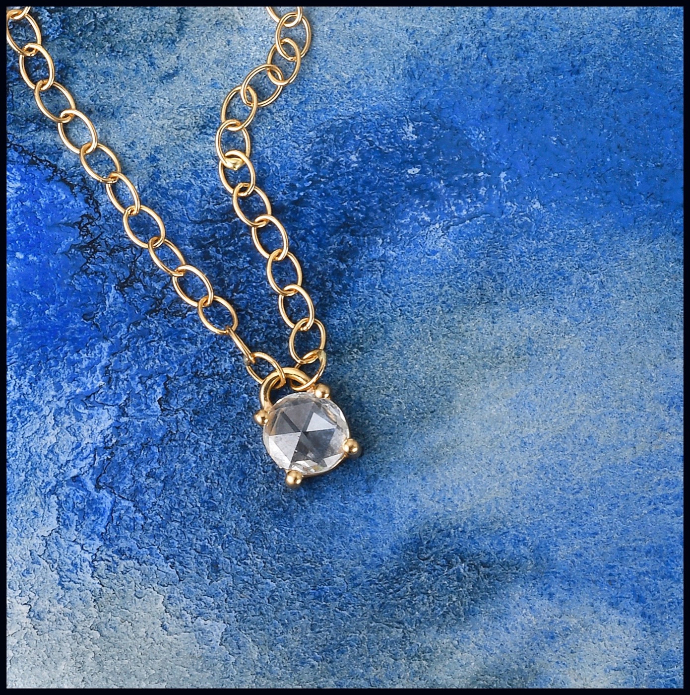 a single rose cut diamond on a delicate gold chain